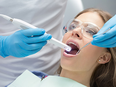 A dental professional using a digital device to scan a patient s teeth during a dental appointment.