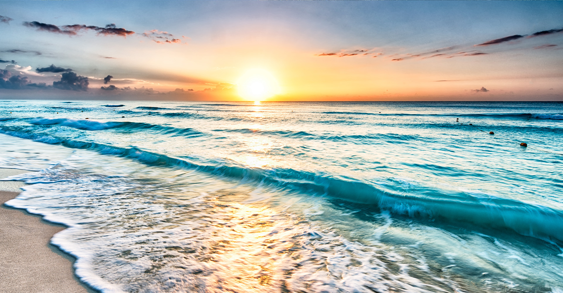 Beautiful sunset over a serene ocean with waves gently lapping the shore.