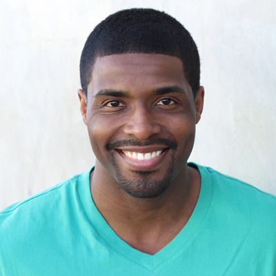 An elderly couple sharing a warm embrace, with the man wearing a beard and both smiling at the camera.