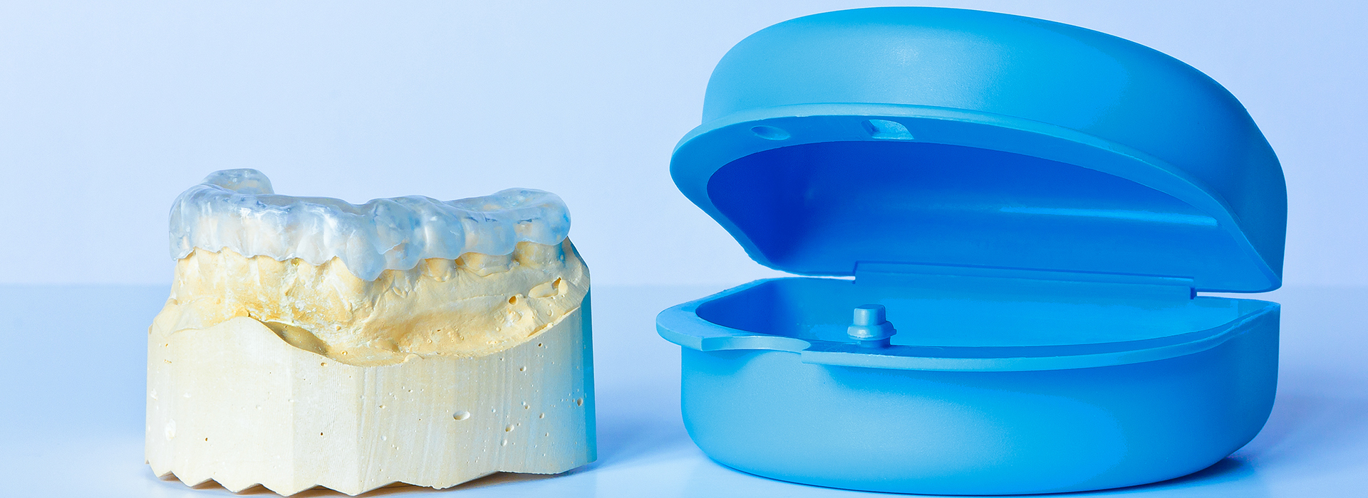 The image shows a blue plastic dental implant and a yellow dental crown, both commonly used in dentistry.