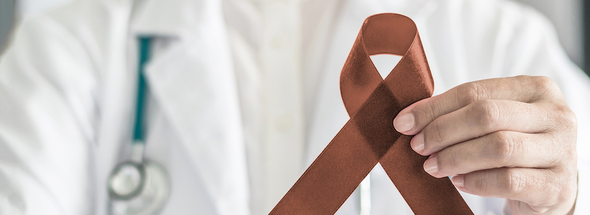 The image features a medical professional holding up a red ribbon, which is commonly associated with awareness for various causes, often related to health or disease.