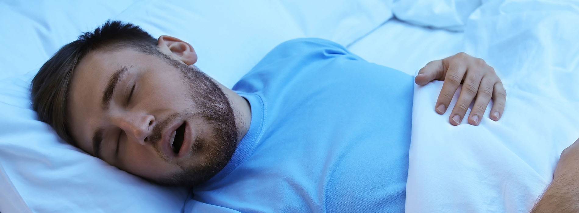 The image shows a man sleeping in bed with his mouth open.