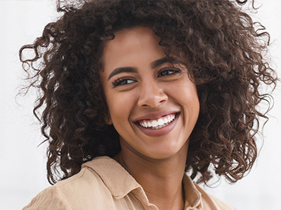 A smiling woman with curly hair, posing for a portrait against a light background.